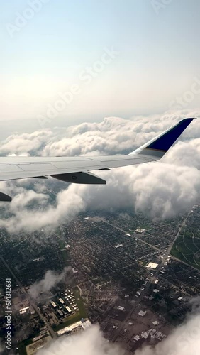 An airplane has just taken off from O'Hare International Airport and is flying high above suburban Chicago, Illinois, USA. Flying above the clouds with views of the city grid.
