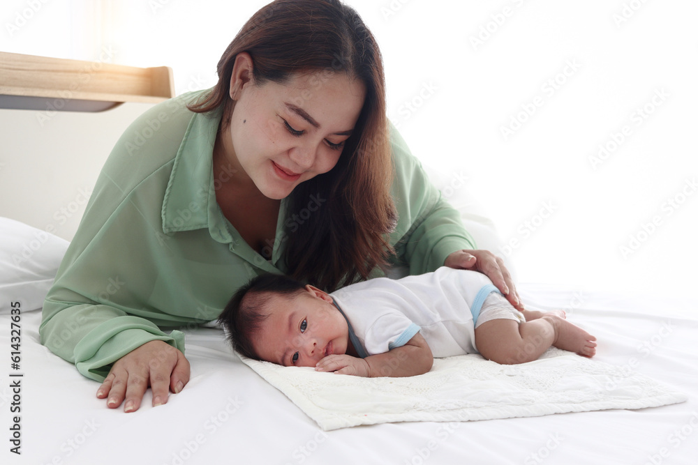 Mother gentle touching newborn infant baby boy on bed in white bedroom, lovely family mom and child stand time together, parent take care kid, overweight mother with fat body after childbirth. Mother gentle touching newborn infant baby boy on bed in white bedroom, lovely family mom and child stand time together, parent take care kid, overweight mother with fat body after childbirth.