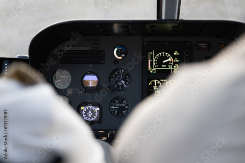 Helicopter pilot at controls with instrument panel showing airspeed and altimeter, among with other displays.  Somewhat abstract with a white sky seen out of the cockpit window.