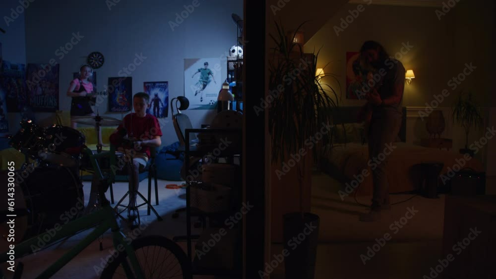 Man plays electric guitar in bedroom with flickering lights. Young boy and girl living next door, play drum kit and ukulele at night. View of two rooms separated by wall. Concept of neighbourhood. Man plays electric guitar in bedroom with flickering lights. Young boy and girl living next door, play drum kit and ukulele at night. View of two rooms separated by wall. Concept of neighbourhood.