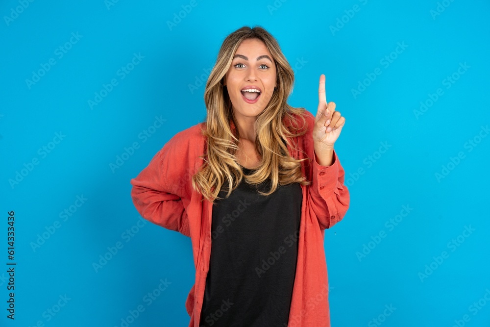 young beautiful blonde woman wearing overshirt holding finger up having idea and posing young beautiful blonde woman wearing overshirt holding finger up having idea and posing
