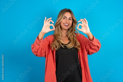 Fotografija young beautiful blonde woman wearing overshirt showing both hands with fingers in OK sign