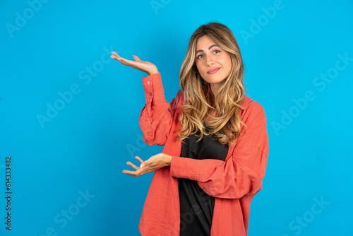 young beautiful blonde woman wearing overshirt pointing aside with both hands showing something strange and saying: I don't know what is this. Advertisement concept.