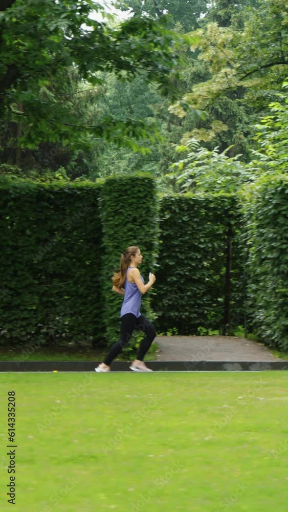 Vertical Screen: Fit woman in sportswear jogging against garden maze in slow motion. Tracking shot training outside in the morning. Healthy lifestyle and outdoor activity. Concept of fitness Vertical Screen: Fit woman in sportswear jogging against garden maze in slow motion. Tracking shot training outside in the morning. Healthy lifestyle and outdoor activity. Concept of fitness