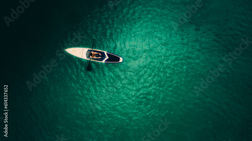 Aerial shot of beautiful green lagoon at hot summer day with small boat. Top view of girl in the boat. © bundid