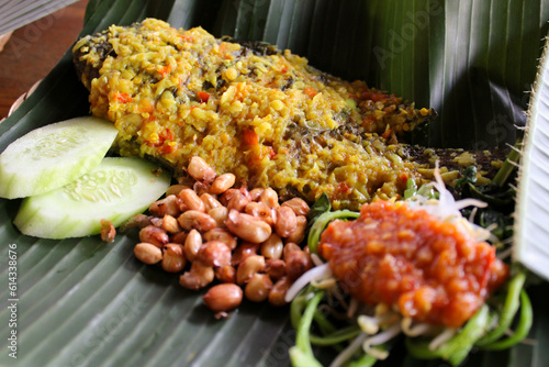 Traditional balinese food, Mujair Nyat-nyat, served on fresh banana leaf plating with various side dishes. Taken at Penglipuran Village, Bali, Indonesia photo