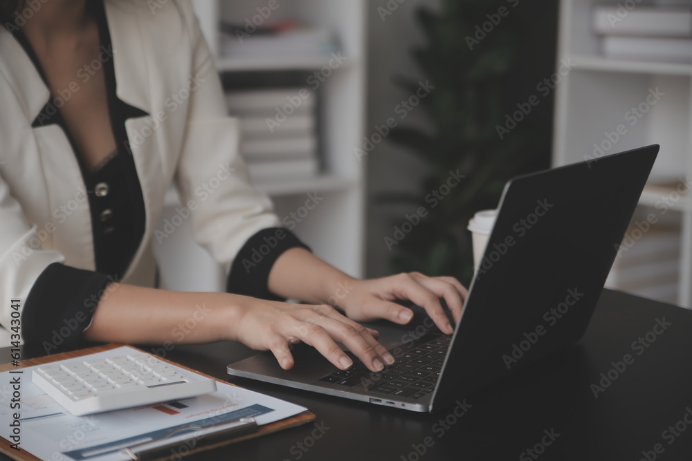 Asian Business woman using calculator and laptop for doing math finance on an office desk, tax, report, accounting, statistics, and analytical research concept Asian Business woman using calculator and laptop for doing math finance on an office desk, tax, report, accounting, statistics, and analytical research concept