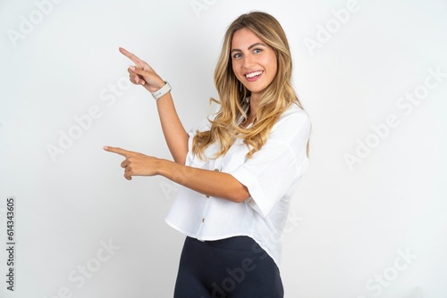 Young caucasian business woman wearing white shirt over white background indicating finger empty space showing best low prices, looking at the camera photo