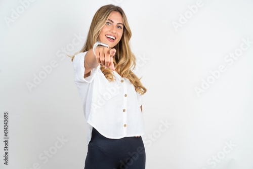 Young caucasian business woman wearing white shirt over white background pointing at camera with a satisfied, confident, friendly smile, choosing you