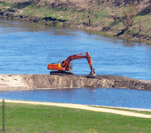 Orange excavator works on the river bank