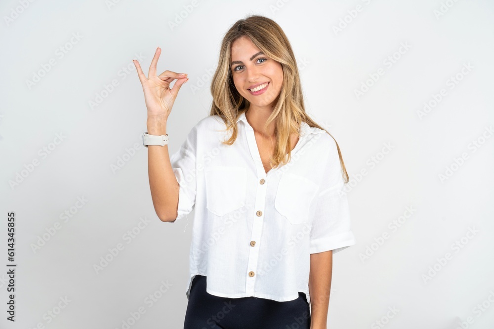 young blonde woman wearing white shirt over white studio background pointing up with hand showing up seven fingers gesture in Chinese sign language Qi«. young blonde woman wearing white shirt over white studio background pointing up with hand showing up seven fingers gesture in Chinese sign language Qi«.