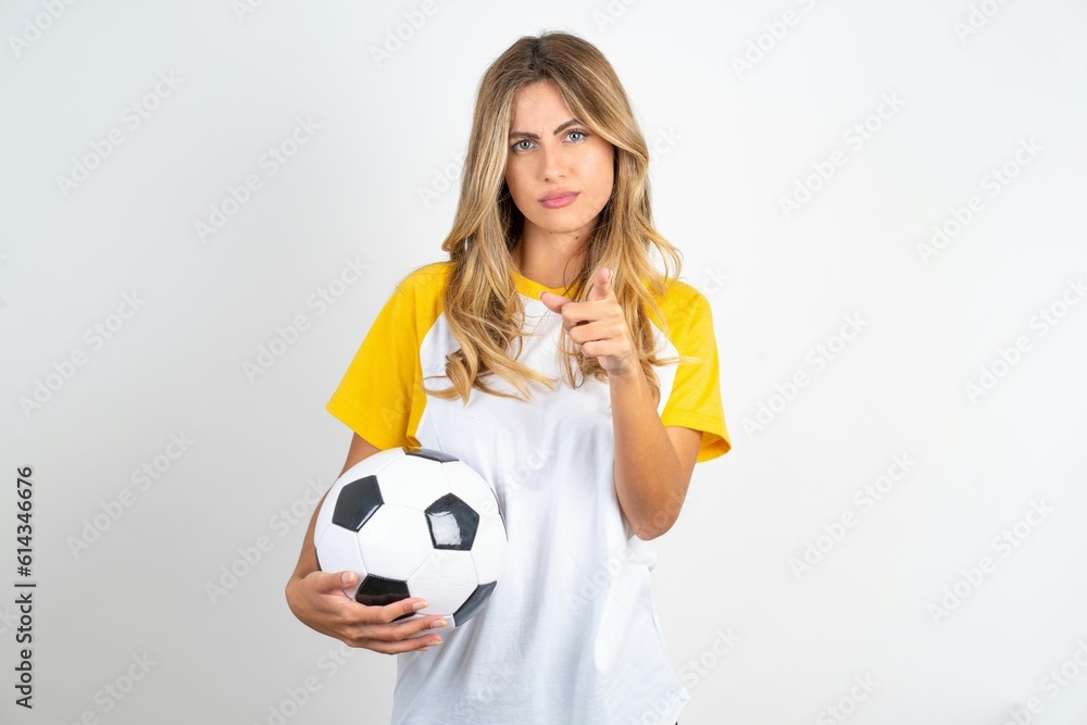 Young beautiful woman wearing football T-shirt over white background frustrated and pointing to the front Young beautiful woman wearing football T-shirt over white background frustrated and pointing to the front