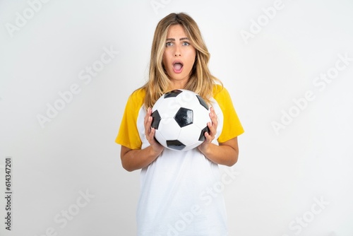 Upset Young beautiful woman wearing football T-shirt over white background touching face with two hands © Jihan