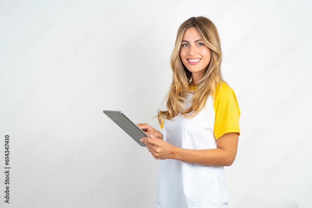 Photo of happy cheerful smart Young beautiful woman wearing football T-shirt over white background hold tablet browsing internet Photo of happy cheerful smart Young beautiful woman wearing football T-shirt over white background hold tablet browsing internet