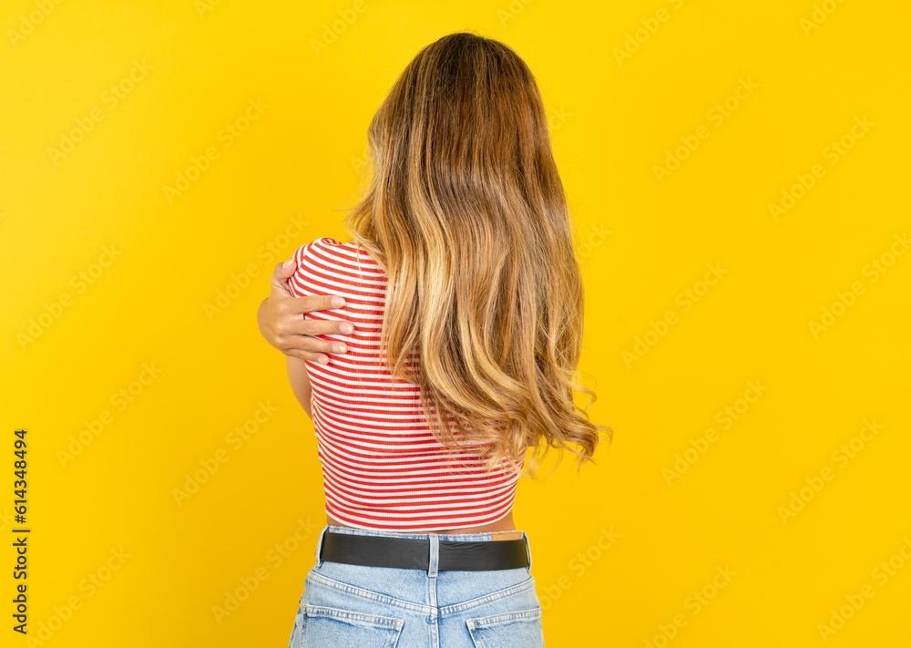 Young beautiful blonde woman wearing striped t-shirt over yellow studio background hugging herself happy and positive from backwards. Self love and self care Young beautiful blonde woman wearing striped t-shirt over yellow studio background hugging herself happy and positive from backwards. Self love and self care