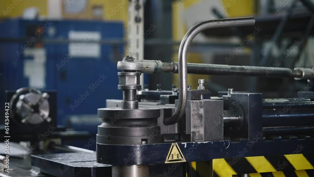 A worker in production bends a metal pipe using a special pipe bending machine. Cold deformation of metal A worker in production bends a metal pipe using a special pipe bending machine. Cold deformation of metal