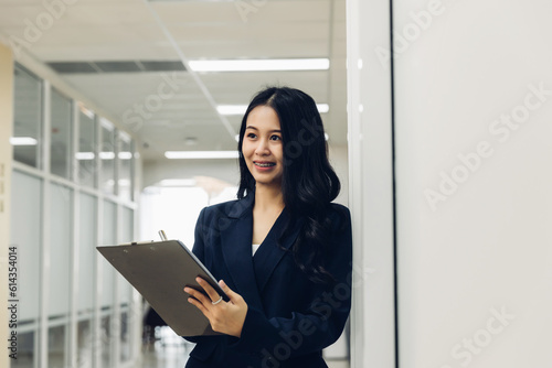 Woman holds a chick list and a pen. Stand up in the modern office. Women leader the new company self-confident. Professional Confident business expert.