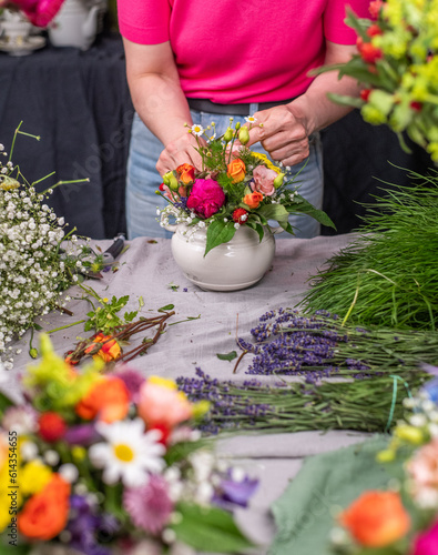 Florist arrangiert bunte Blumen in einem Gefäß aus Keramik, Blumengesteck mit frischen Blumen, 