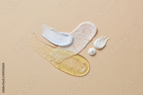 Different cosmetic textures of face cream, serum and lotion on beige background. Cosmetics induce a smoother feel and appearance to the skin