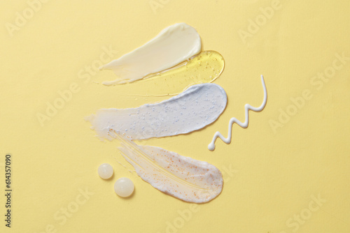 On the light yellow background, four smears of cosmetic texture in yellow, blue and white color are decorated. Gentle skin care