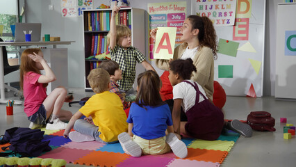 Female teacher hold flashcard with letter a teaching preschool kids alphabet