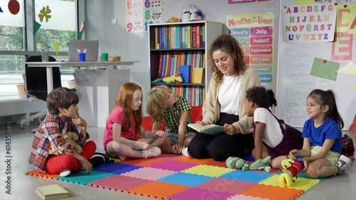 Female teacher reading story to group of elementary pupils in school classroom