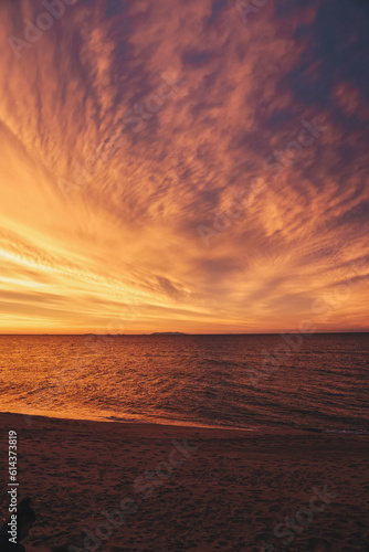 Sonnenuntergang am Strand mit Blick auf das Meer und leuchtendem Himmel, Sardinien, Italien