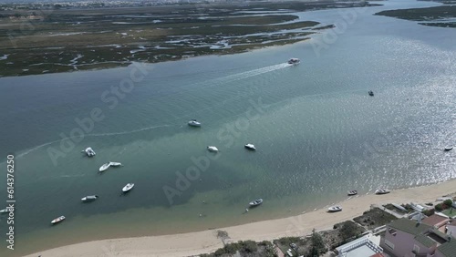 aerial view of a ferry gracefully sailing with tourists across the Ria Formosa Lagoon during low tide, offering a glimpse of the serene beauty of Faro Island in Portugal.