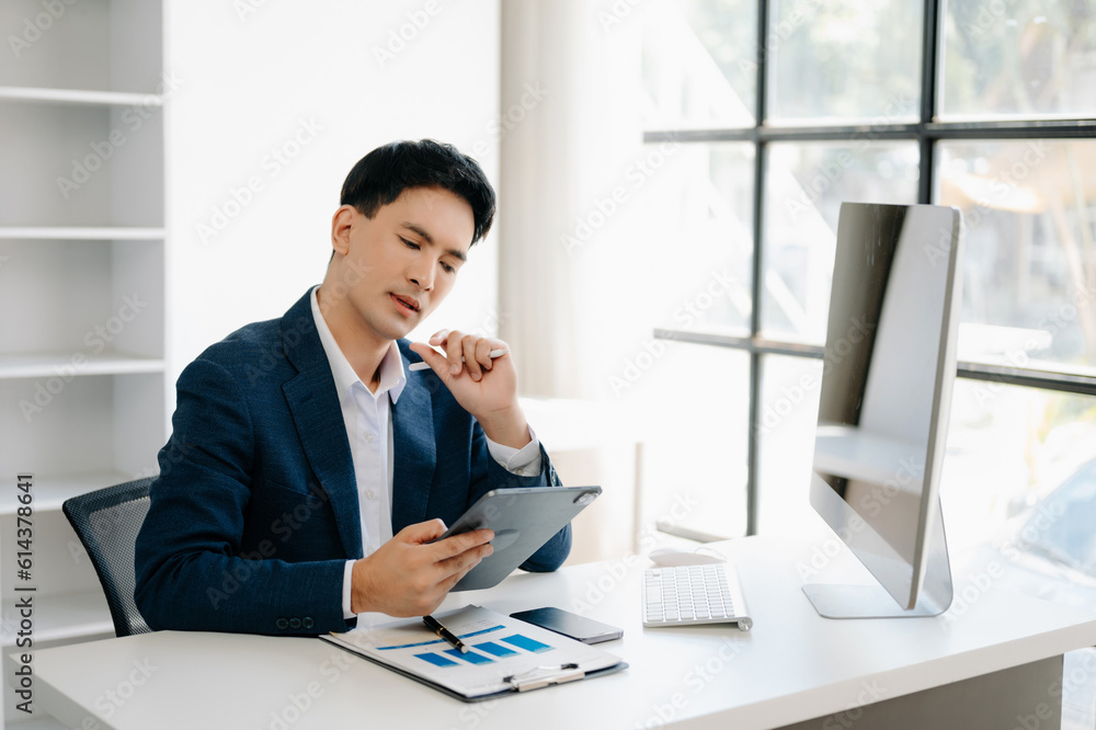 Business man using tablet and laptop for doing math finance on an office desk, tax, report, accounting, statistics, and analytical research concept in office