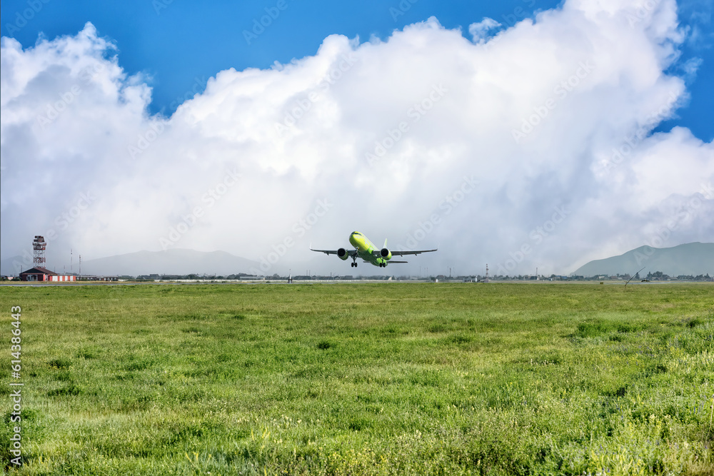 Fototapeta premium A big yellow jet taking off from the airport on background of cloudy blue sky.