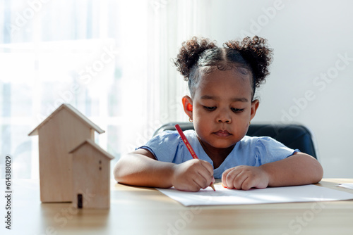 A young African American girl paints with crayons on a white sheet in her living room. preschool concept having fun spend free time alone