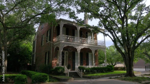 Historic home with iron fence and old Southern Live Oak trees in downtown Mobile, Alabama with gimbal video walking forward at an angle. photo