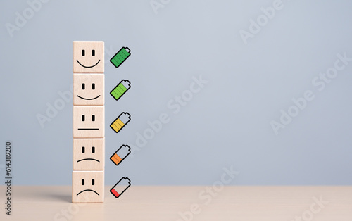 Mentality happiness care. Emotion face symbol on stacked wooden blocks with full to empty battery icons. Life satisfaction level and evaluation, World mental health day. Health and wellness review.