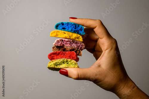 Set of six tasty multicolored blanks of macaron broken in half in female hands