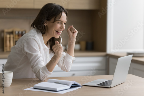 Fotografija Joyful young woman look at notebook screen, reads good news, celebrate online lo