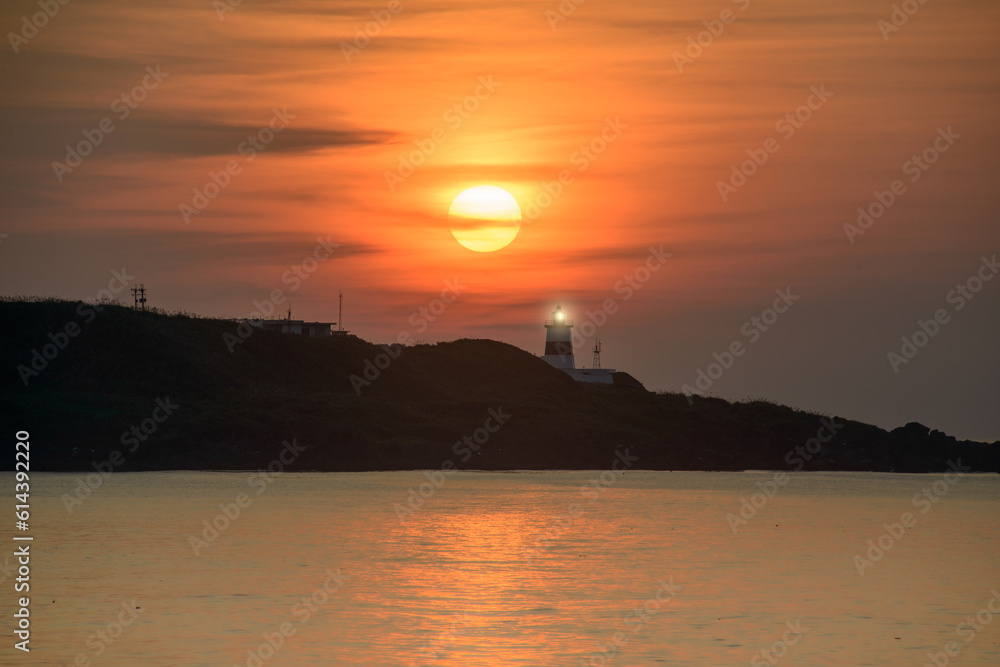 At dusk, the sun is above the lighthouse. The Fugui Cape Lighthouse in Shimen. Taiwan