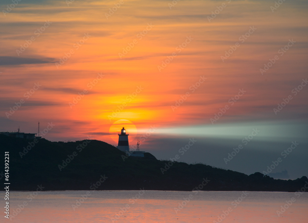 At dusk, the sun is behind the lighthouse. The Fugui Cape Lighthouse in Shimen. Taiwan At dusk, the sun is behind the lighthouse. The Fugui Cape Lighthouse in Shimen. Taiwan