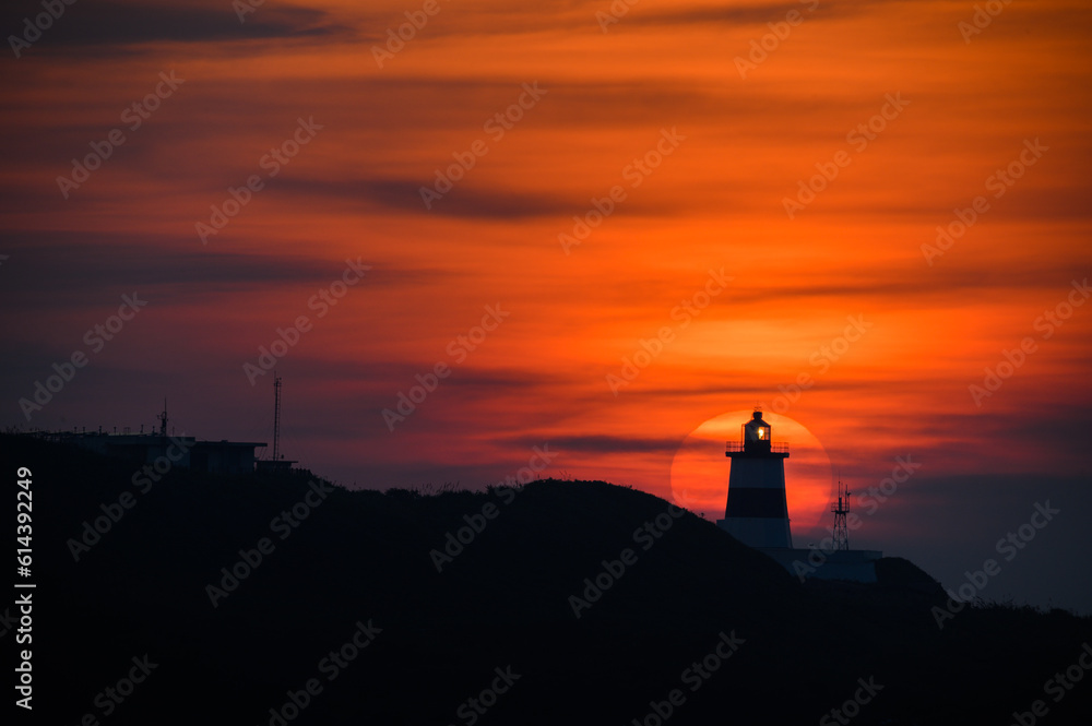 At dusk, the sun is behind the lighthouse. The Fugui Cape Lighthouse in Shimen. Taiwan