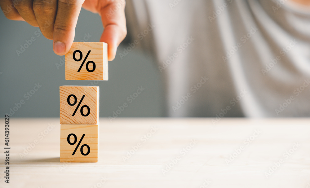 Concept of interest rate and financial rates. Hand placing a wooden cube block on top, symbolizing an increasing trend, with an upward direction icon and percentage symbol. - obrazy, fototapety, plakaty 