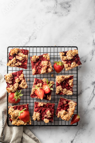 Strawberry granola bars on baking cooling rack white marble background. Delisious homemade oat squares for breakfast top view, text space