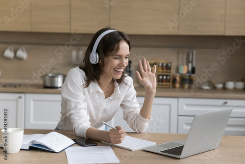 Young happy woman in headphones makes videocall, enjoy distance conversation through videoconference application, receive new knowledge, improve foreign language skill. Virtual meeting event, e-learn