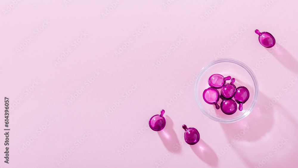 Vitamin capsules in pink, purple color, closeup on pink background, top view