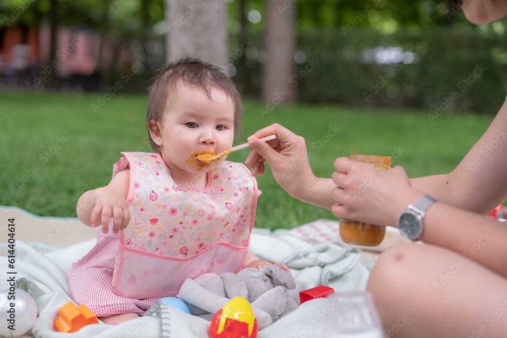 woman feeding her beautiful little daughter - mother hand and close up portrait of adorable and happy baby girl eating baby porridge from spoon in health and nutrition concept woman feeding her beautiful little daughter - mother hand and close up portrait of adorable and happy baby girl eating baby porridge from spoon in health and nutrition concept