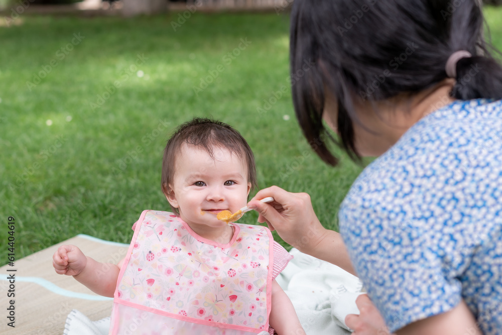 woman feeding her beautiful little daughter - mother hand and close up portrait of adorable and happy baby girl eating baby porridge from spoon in health and nutrition concept woman feeding her beautiful little daughter - mother hand and close up portrait of adorable and happy baby girl eating baby porridge from spoon in health and nutrition concept