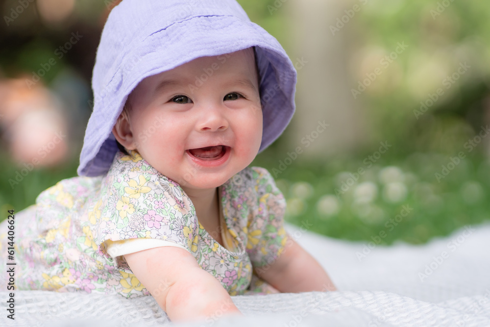 adorable and happy baby girl in summer hat embraces the joys of playfulness on a soft blanket. Laughing as she explores the natural wonders of an outdoors city park adorable and happy baby girl in summer hat embraces the joys of playfulness on a soft blanket. Laughing as she explores the natural wonders of an outdoors city park