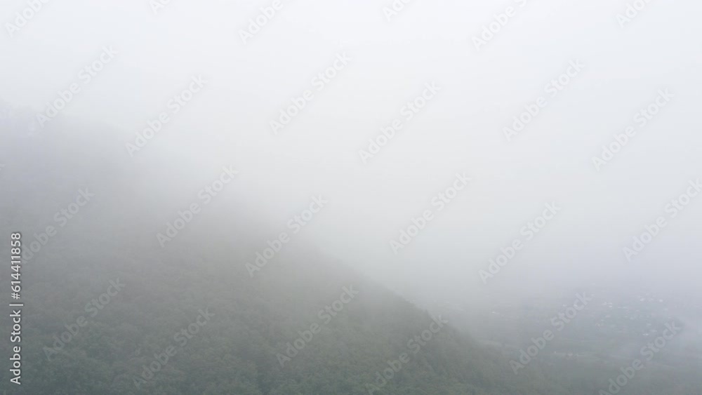Aerial drone view of morning mist fog rolling in over forest on beautiful mountains background at summer cloudy day. Tree peaks stand out, pristine and untouched nature reserve, nature background Aerial drone view of morning mist fog rolling in over forest on beautiful mountains background at summer cloudy day. Tree peaks stand out, pristine and untouched nature reserve, nature background