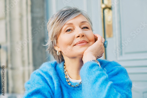Outdoor portrait of beautiful 55 - 60 year old woman, wearing blue pullover