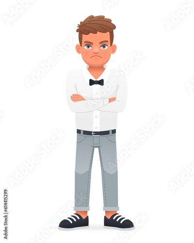 A disgruntled little boy stands with his arms crossed. A beautiful cute schoolboy child in a white shirt with a bow tie.