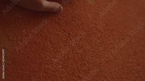 Slow motion man hand touching terracotta wall photo