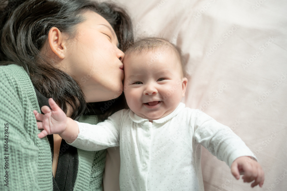 love and playfulness, a young Asian Chinese woman joyfully engages with her baby girl on the bed. Their laughter creates precious memories together bonding in pure happiness love and playfulness, a young Asian Chinese woman joyfully engages with her baby girl on the bed. Their laughter creates precious memories together bonding in pure happiness